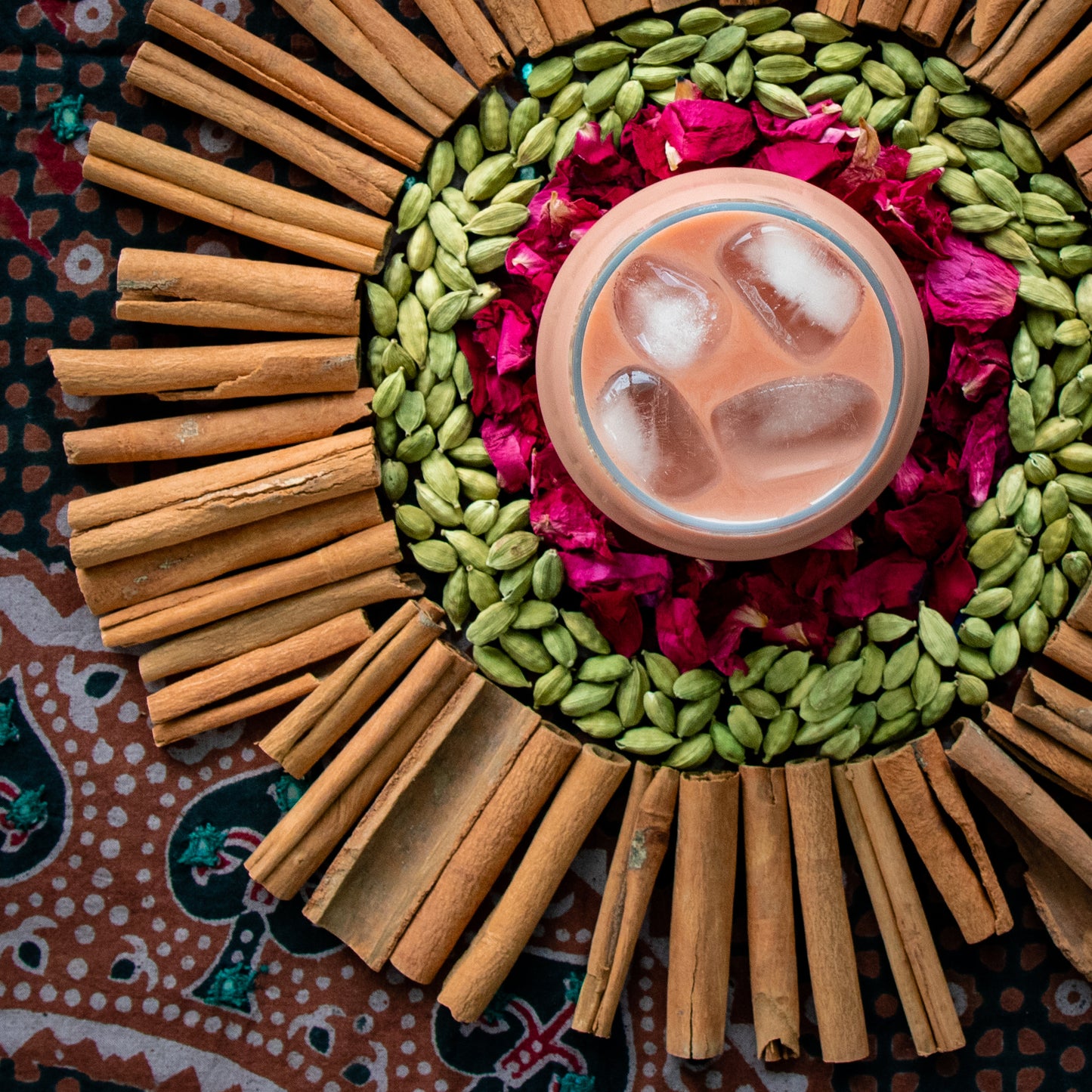 Cold brew pink coffee with rose petals, cardamom, and cinnamon on a traditional kashmiri tablecloth